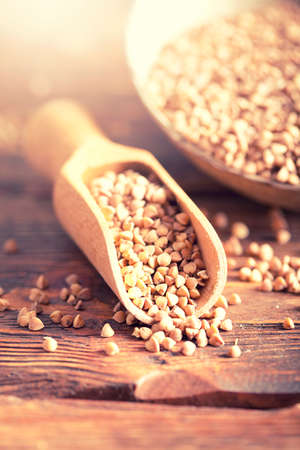 Buckwheat in scoop and bowl on wooden tableの写真素材