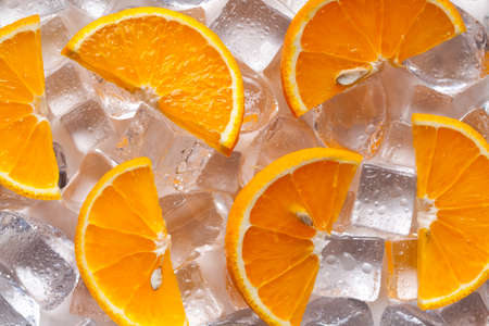 Pieces of orange fruit on ice cubesの写真素材