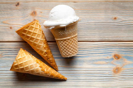 Ice cream and empty cones on wooden backgroundの写真素材