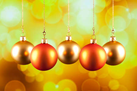 Four Christmas baubles on yellow backgroundの写真素材