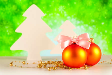 Two Christmas baubles and trees on green backgroundの写真素材