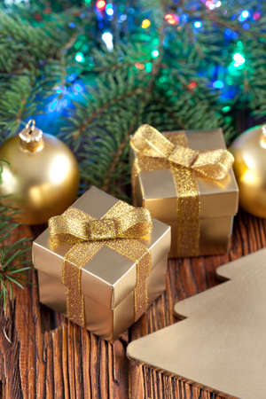 Christmas baubles, gift boxes and spruce branch on wooden backgroundの写真素材