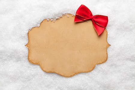 Blank paper card and red bow on snowの写真素材