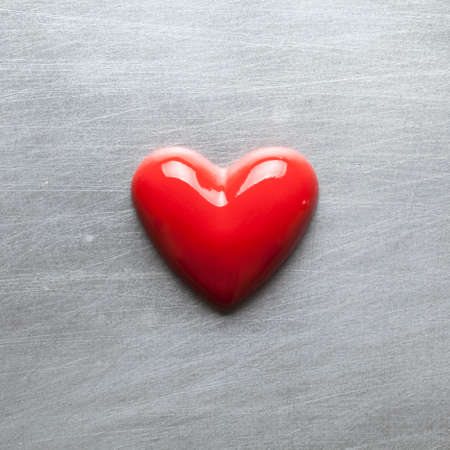 Red heart on a scratched metal plateの写真素材