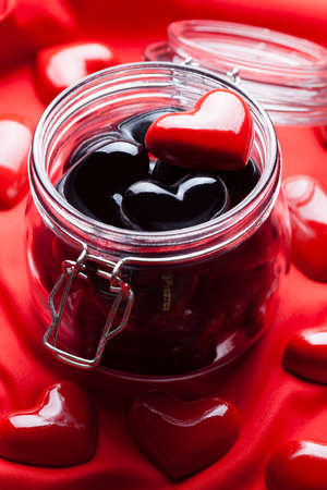 Black and red hearts in jar and fabric backgroundの写真素材