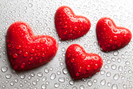 Four statues in the shape of a heart dewy water on a metal surfaceの写真素材