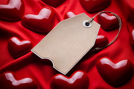 Paper tag and red hearts on fabric backgroundの写真素材