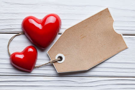 Two red hearts and one paper tag on wooden tableの写真素材