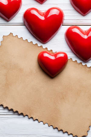 Blank paper sheet and red hearts on wooden tableの写真素材