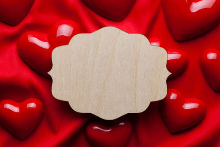 Wooden plate and red hearts on fabric backgroundの写真素材