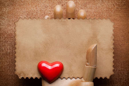 Blank paper sheet in wooden hand and red heart on paper backgroundの写真素材