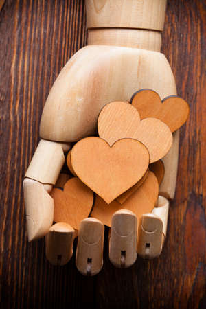 Wooden hearts in wooden hand on old tableの写真素材