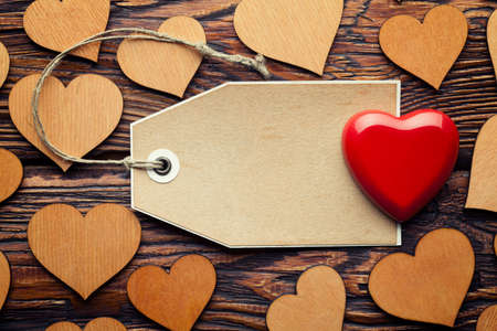 One red and group of wooden hearts and blank paper label on planksの写真素材