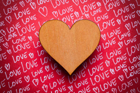 Blank wooden plate in wooden hand and red hearts in backgroundの写真素材