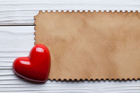 One red heart and blank paper sheet on wooden tableの写真素材