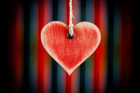 Wooden heart on a string and black and red pattern in backgroundの写真素材
