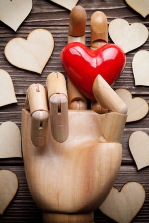 Fake wooden hand and hearts on wooden tableの写真素材