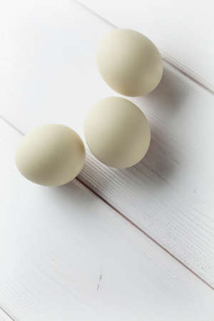 Three eggs on white planksの写真素材