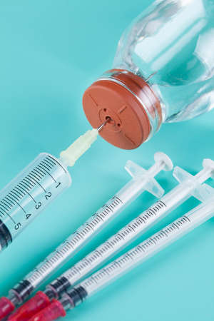 Preparing injection - syringe and glass bottle on blue backgroundの写真素材