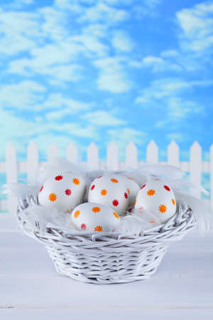 Easter eggs in the basket on blue sky backgroundの写真素材