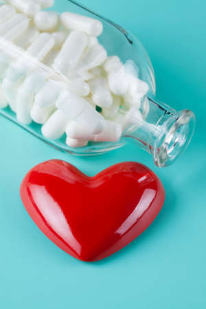 Red figure in the shape of heart and pills as a symbol of health careの写真素材