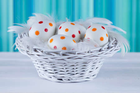 Patterned easter eggs in the basket on wooden tableの写真素材