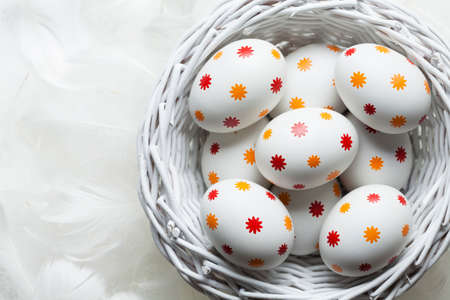 Patterned easter eggs in the basket and white feathersの写真素材