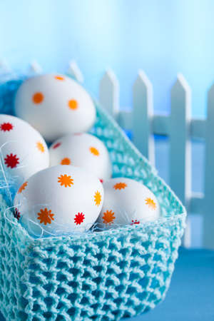 Easter eggs in the basket and white fenceの写真素材
