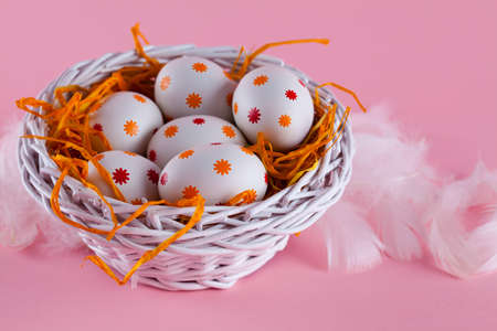 Easter eggs in the nest and basket on pink backgroundの写真素材