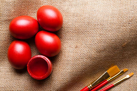 Red easter eggs and paintbrushes on canvasの写真素材