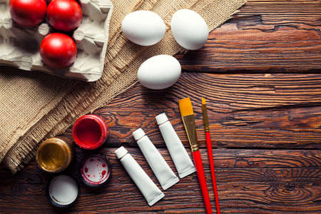 Easter eggs, paint and brushes on wooden tableの写真素材