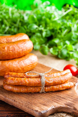 Raw sausage, tomato and fresh herbs on wooden and canvas backgroundの写真素材