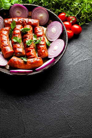 Grilled sausage, herbs and vegetables on black tableの写真素材