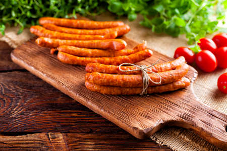 Raw sausage, tomato and fresh herbs on wooden and canvas backgroundの写真素材