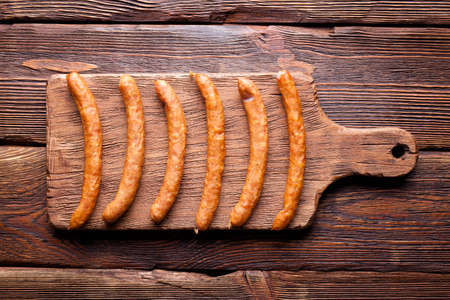 Raw sausage on old damaged cutting board and wooden planksの写真素材