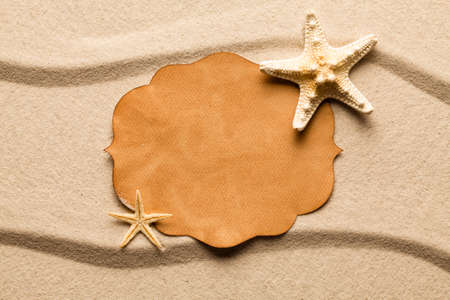 Blank paper label and starfish on beach sand の写真素材