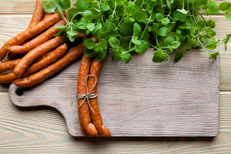 Raw sausage, cutting board and fresh herbs on wooden tableの写真素材