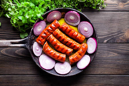 Grilled sausage in a pan and fresh herbs on wooden tableの写真素材