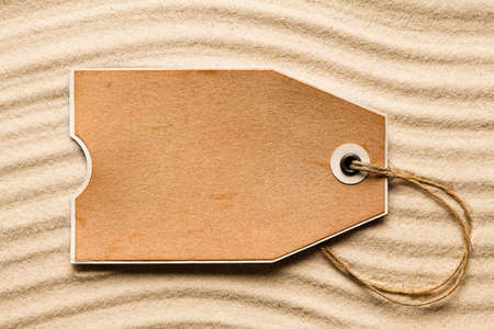 Blank paper label on beach sand