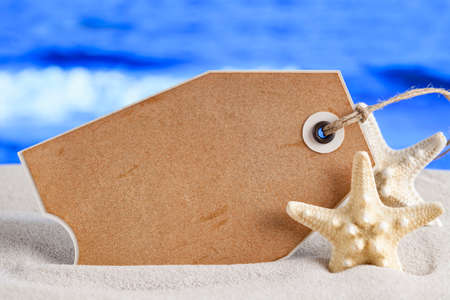 Blank paper label and starfish on beach sand and sea backgroundの写真素材