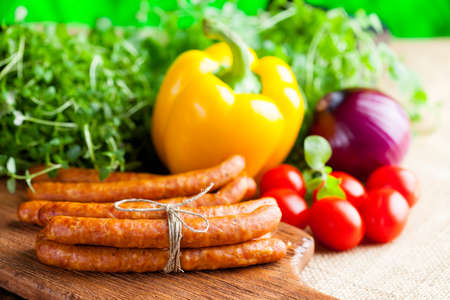 Sausage, herbs and vegetables on wooden and canvas backgroundの写真素材