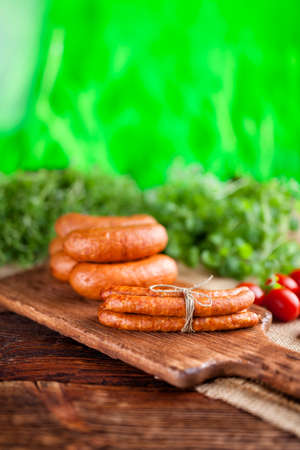 Raw sausage and fresh herbs on green nature backgroundの写真素材