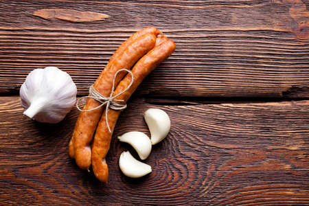Raw sausage and garlic on wooden tableの写真素材