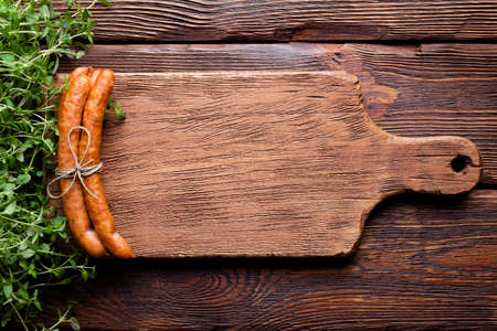 Raw sausage and fresh herbs on wooden tableの写真素材