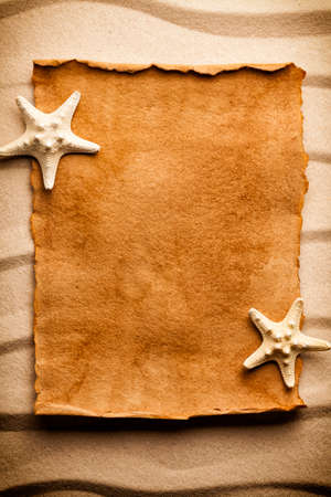 Blank handmade paper sheet and starfish on sandの写真素材