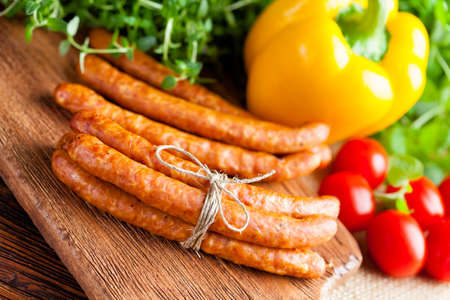 Sausage, herbs and vegetables on wooden and canvas backgroundの写真素材