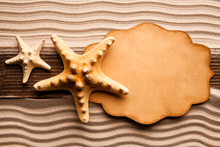 Blank paper sheet and starfish on beach sandの写真素材