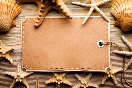 Summer background - paper label, shells and beach sandの写真素材