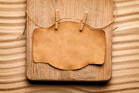 Blank paper label on wooden board and beach sandの写真素材