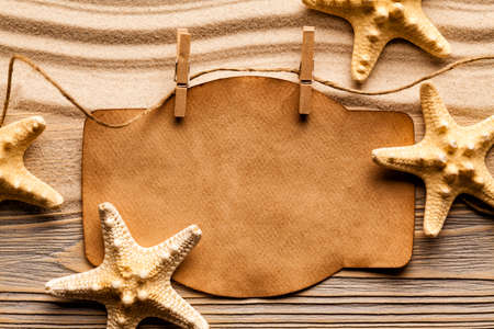 Starfishes and blank paper sheet on beach sandの写真素材